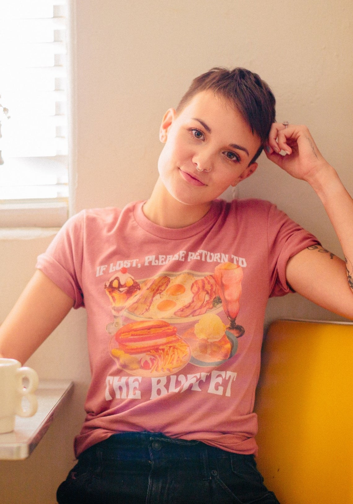 Model wearing faded style shirt that says &quot;If lost, please return to the buffet&quot; with old school images of several different meals and desserts including a hot dog and fries, pie, milkshake, sundae, and bacon and eggs 