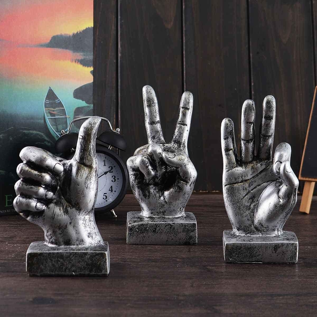 three silver gesture sculptures on a wooden surface