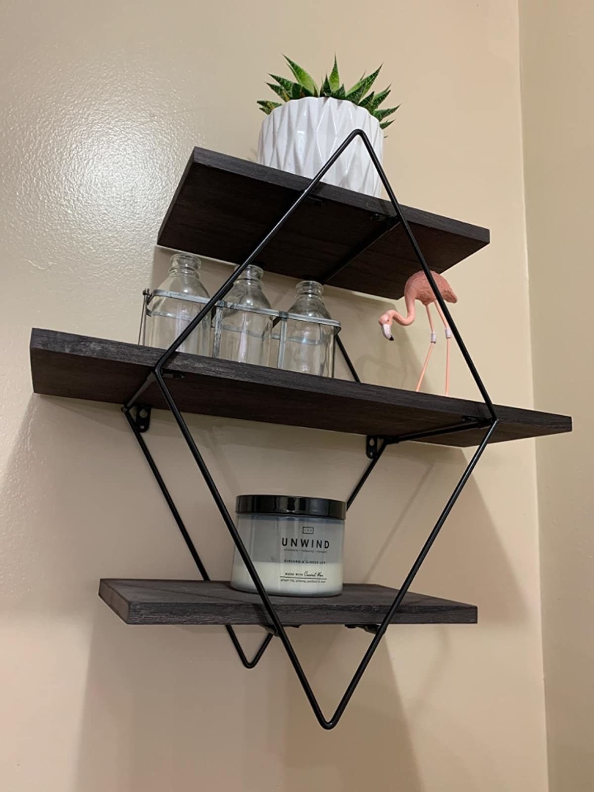 reviewer image of the coffee Befayoo Diamond Floating Shelves mounted on a wall with a plant and candle on the shelves