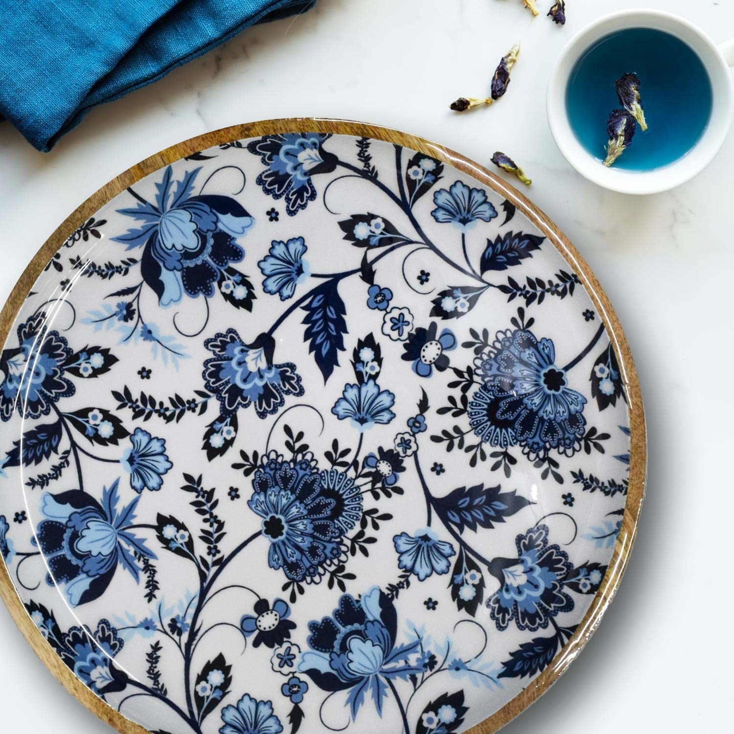 A circular wooden tray with a white and blue floral design.