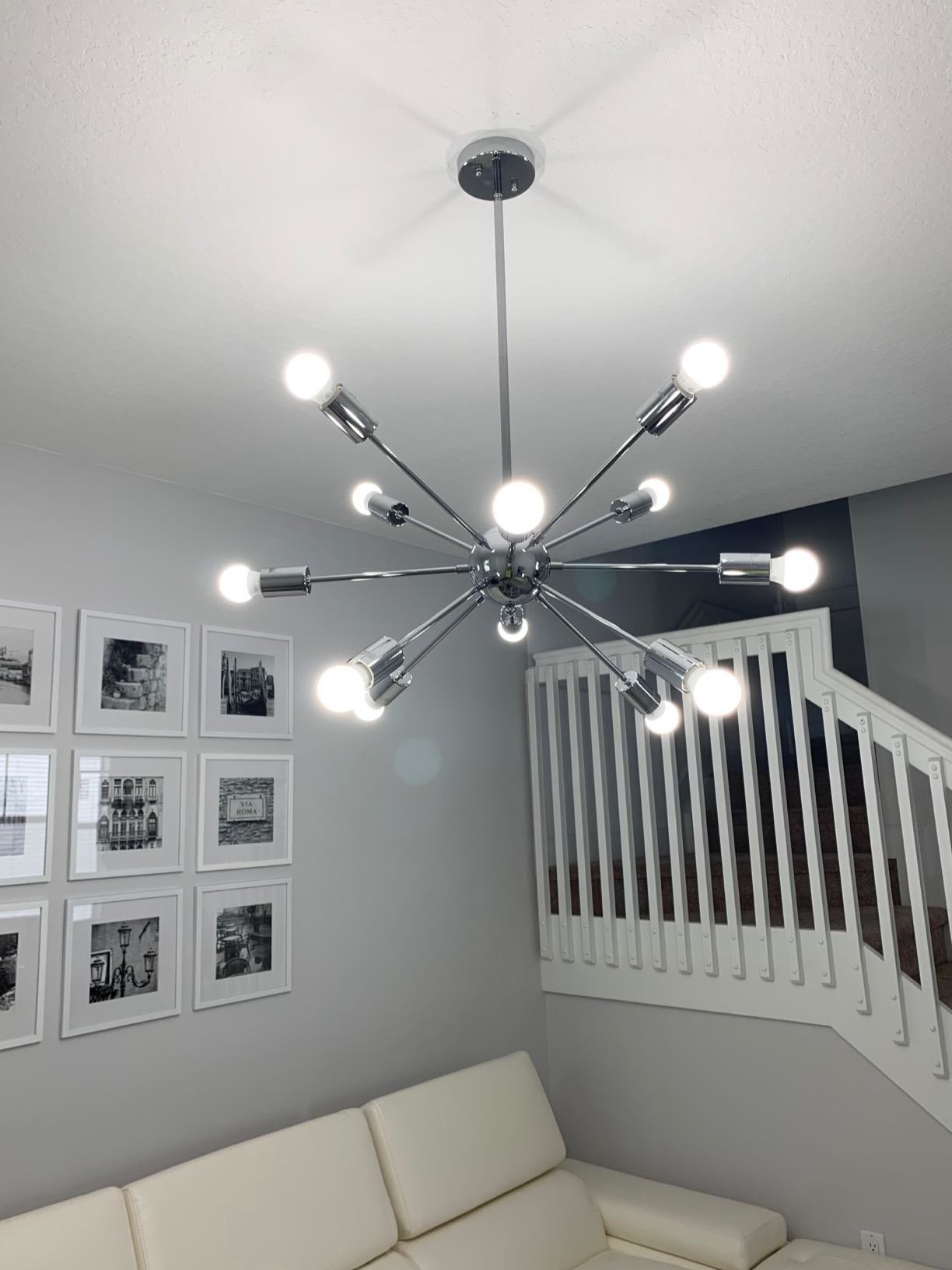reviewer image of the chandelier with 12 silver arms and light bulbs hanging from a celiling