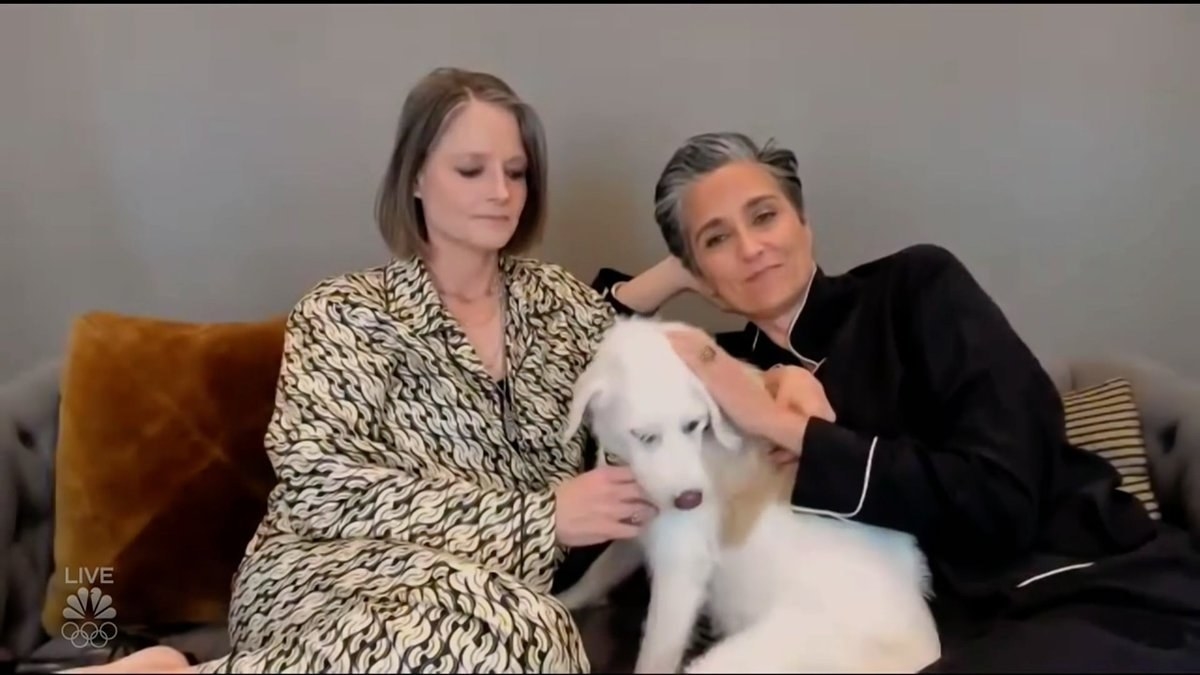 Jodie and Alex relaxing on the couch as they pet their adorable dog