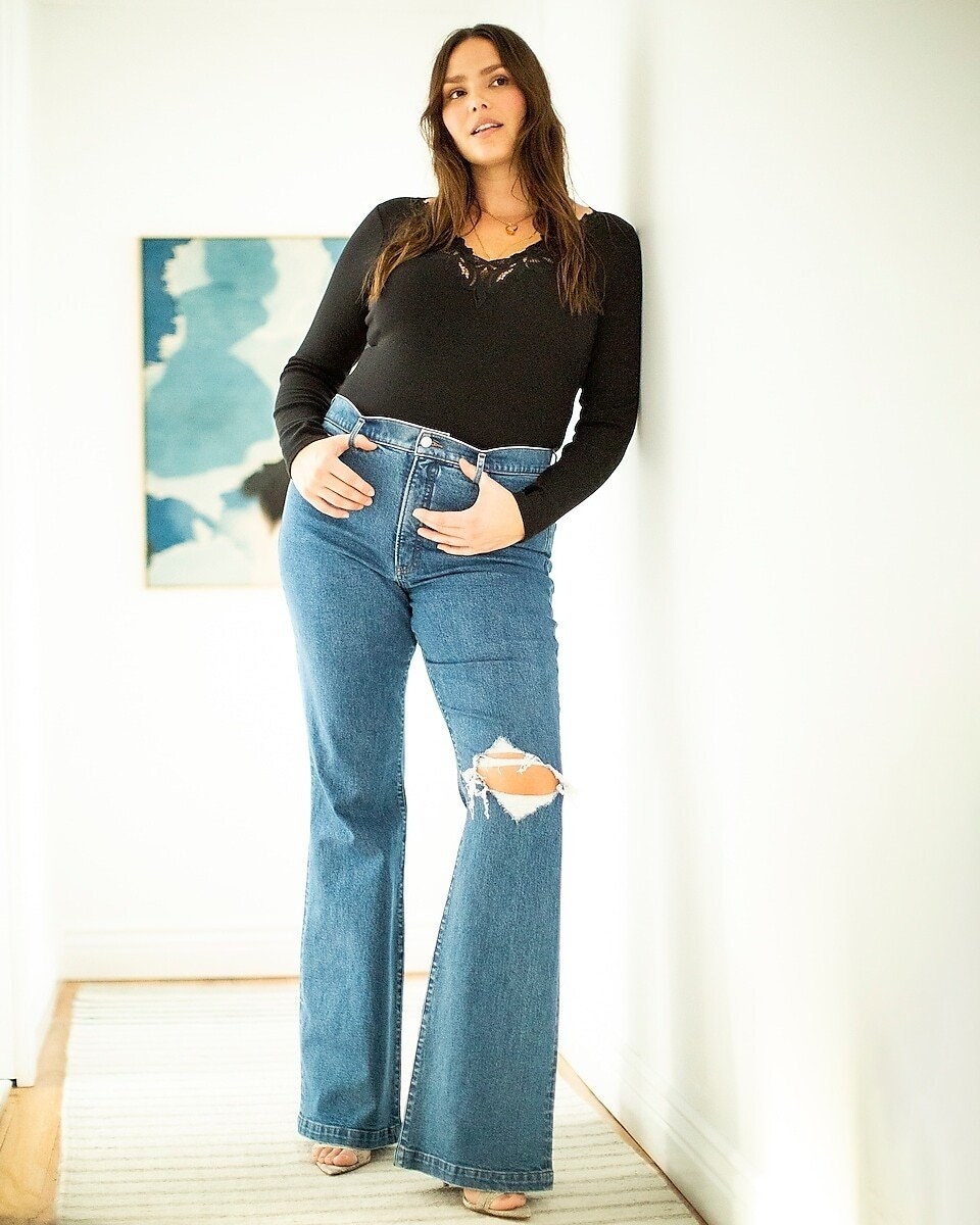 Plus size model wearing the jeans with a black shirt and open-toe heels 
