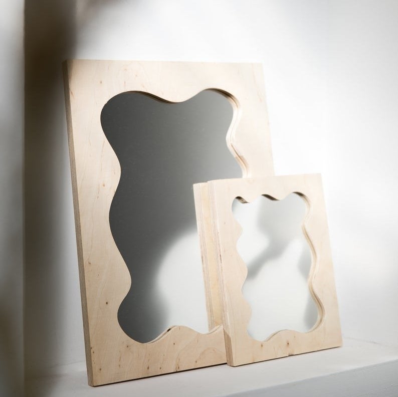 rectangle mirror with light wood frame and squiggle pattern on the inside of the frame