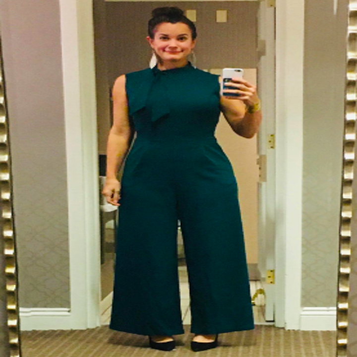 Different reviewer wearing the jumpsuit in green with black heels 