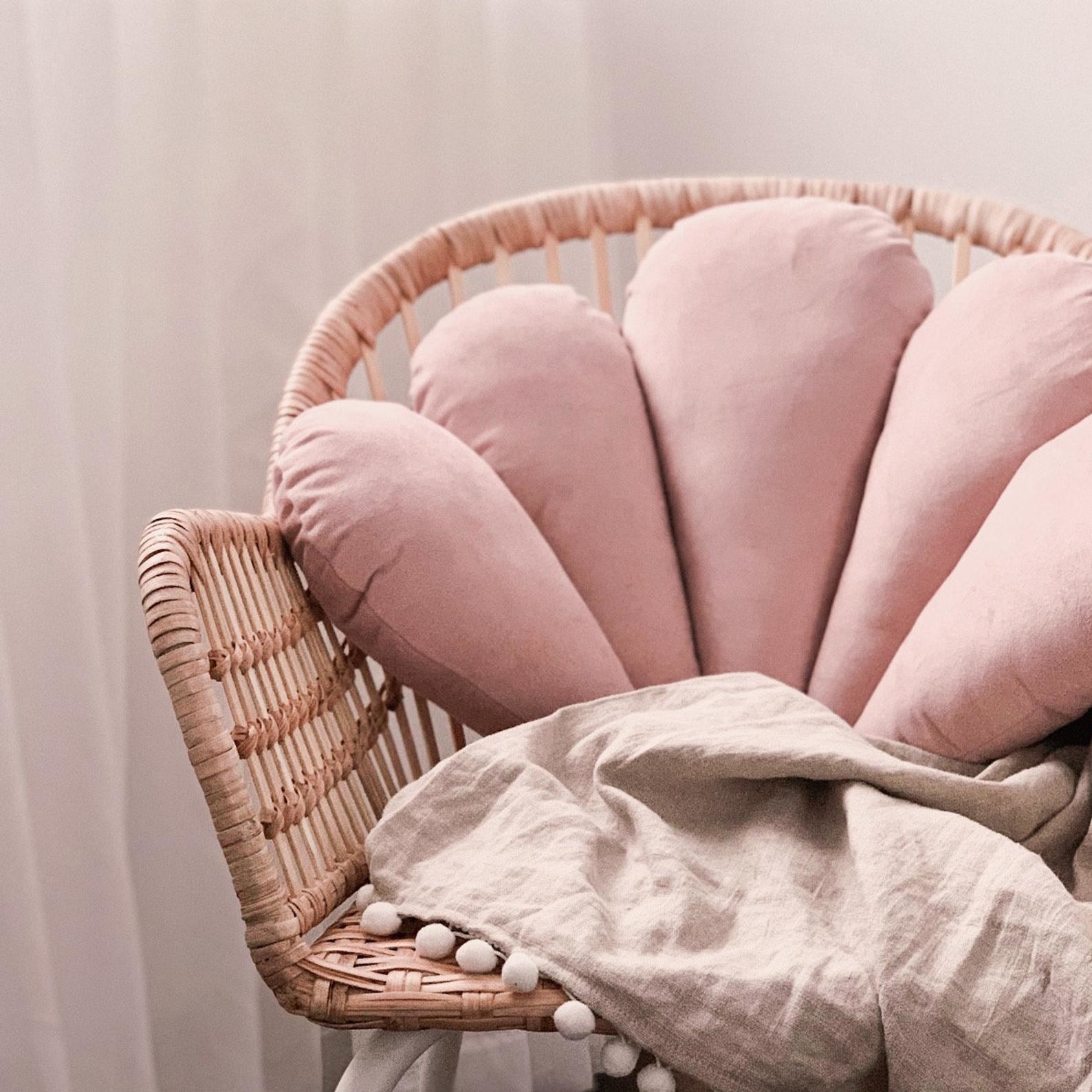 large pink velvet pillow shaped like a seashell in a chair