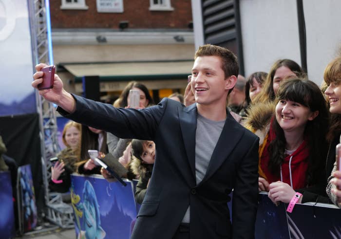 Tom taking a photograph with fans at a premier