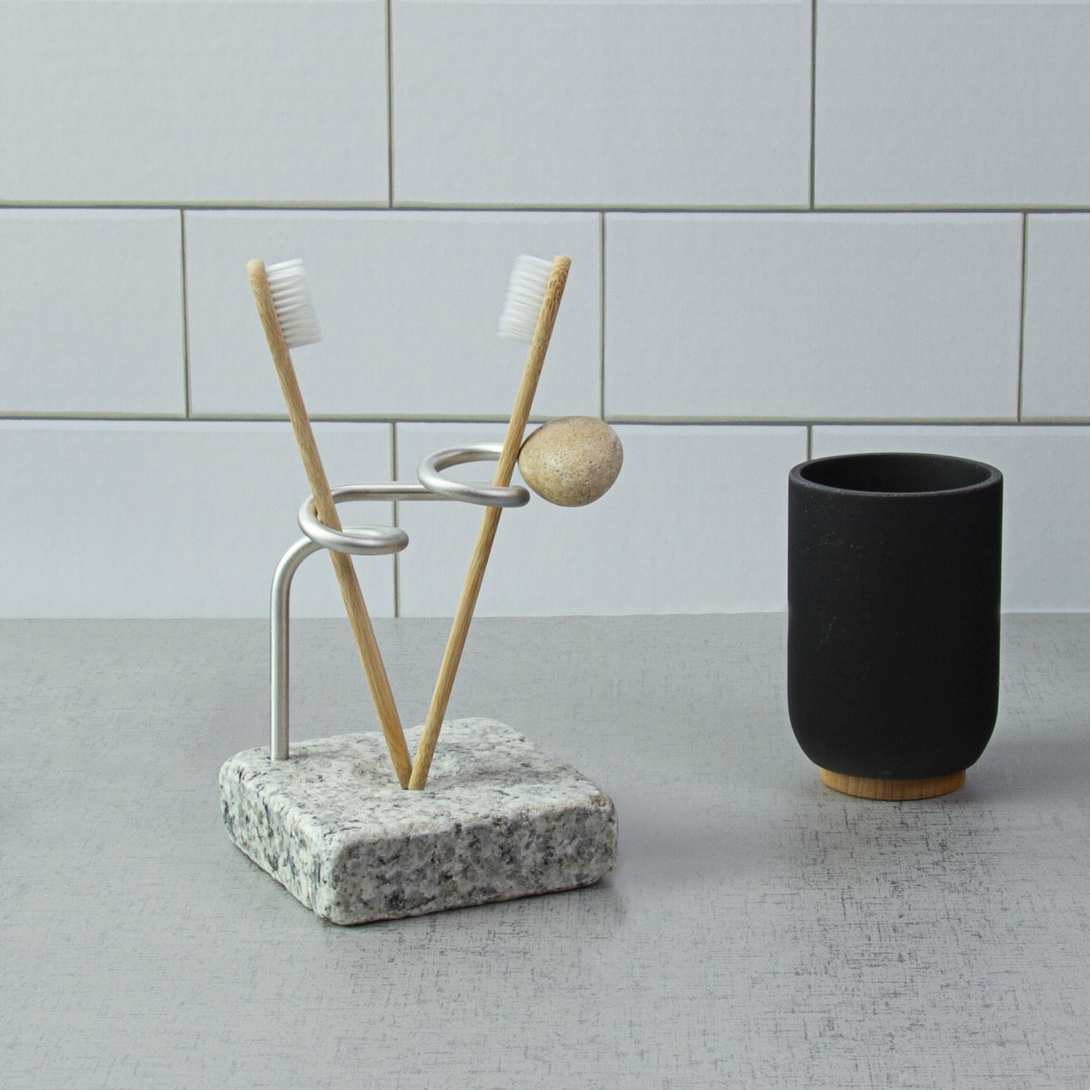 toothbrush holder with marble-like stone base and a swirly silver rod that twists to hold two toothbrushes