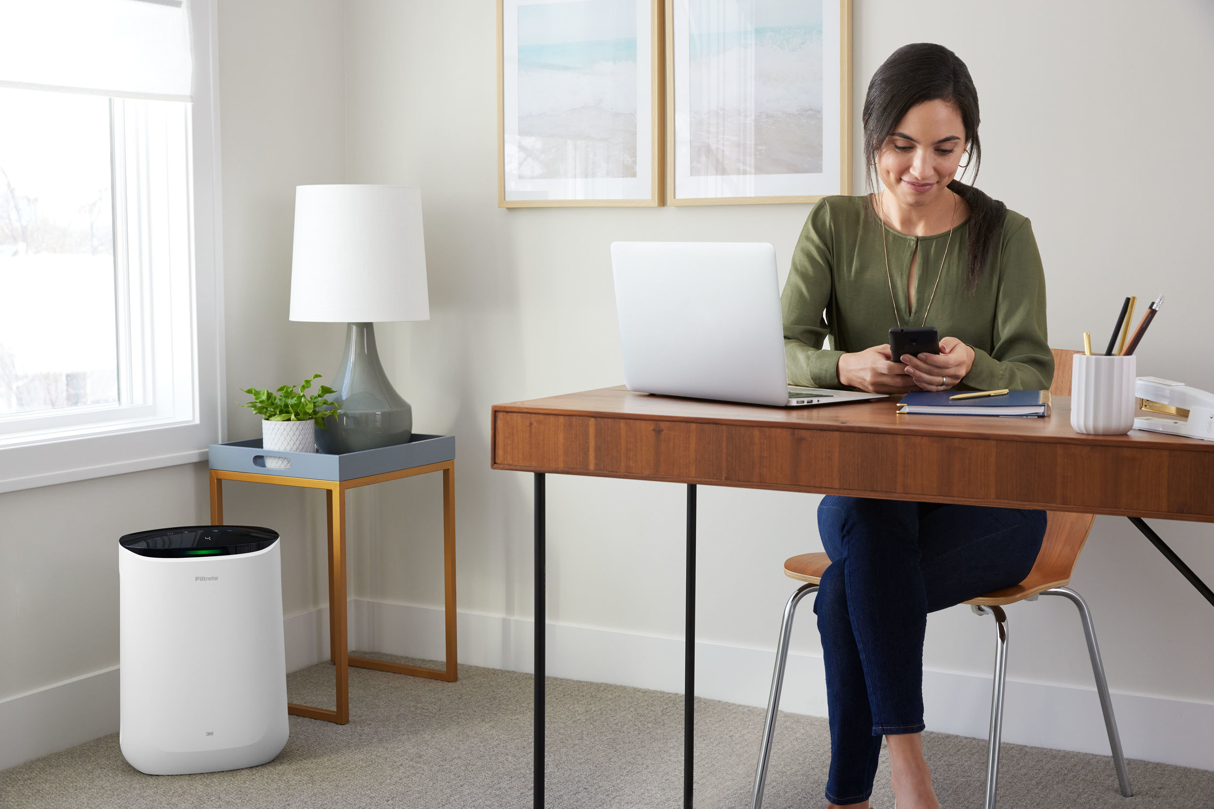 Model sitting at home office desk with white air purifier in corner