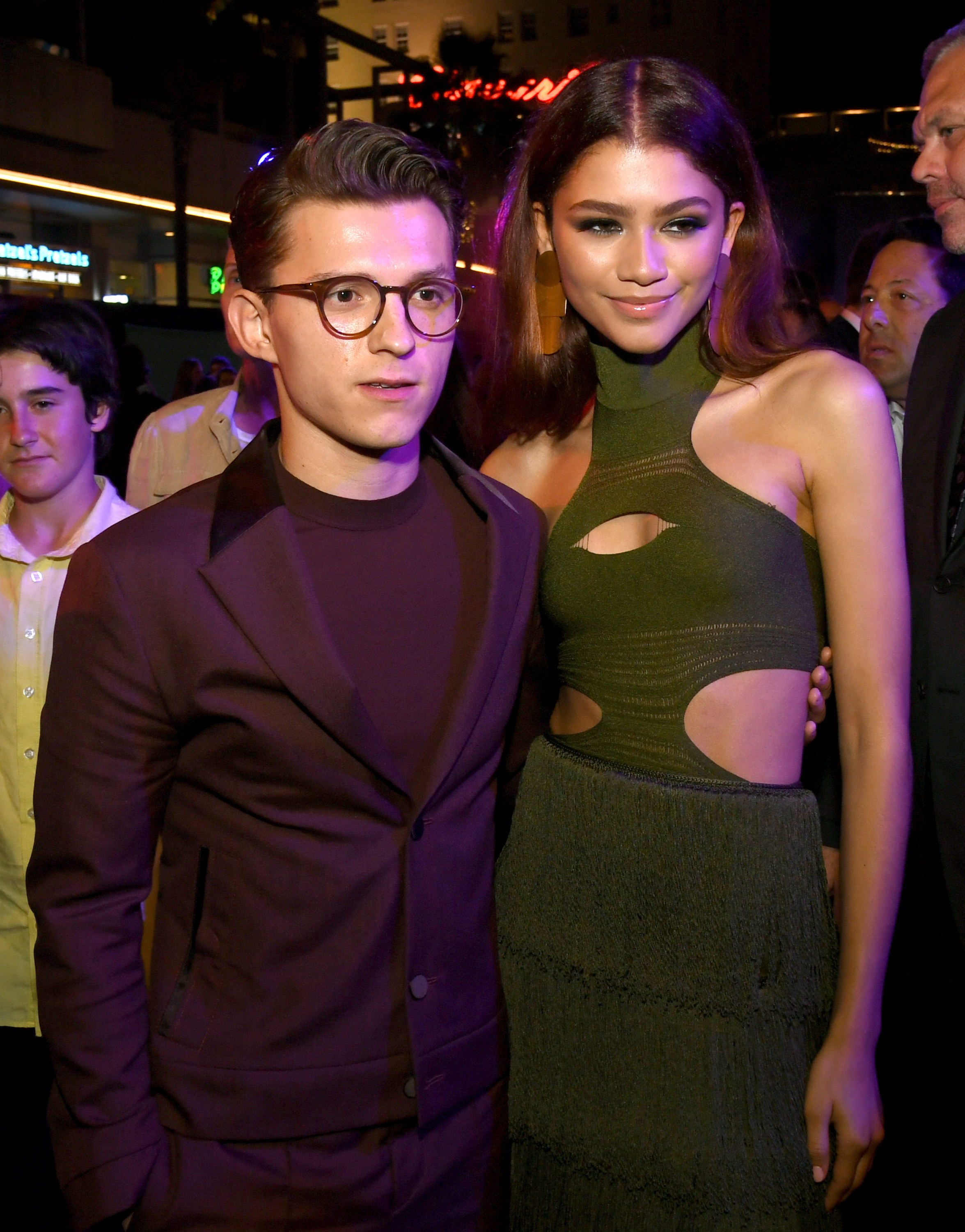 Tom, in a monochrome suit, and Zendaya, in a halter dress with cut-outs, posing together for a photo