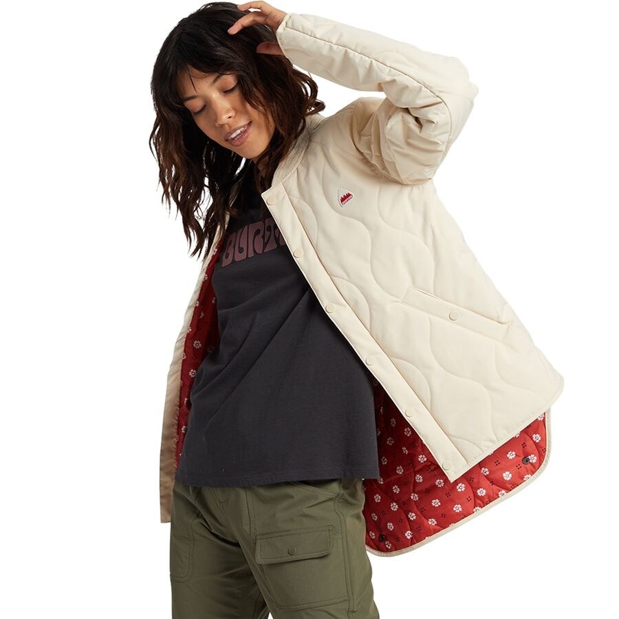 Person wearing lightweight quilted jacket in a cream color. It has red floral fabric inside. 