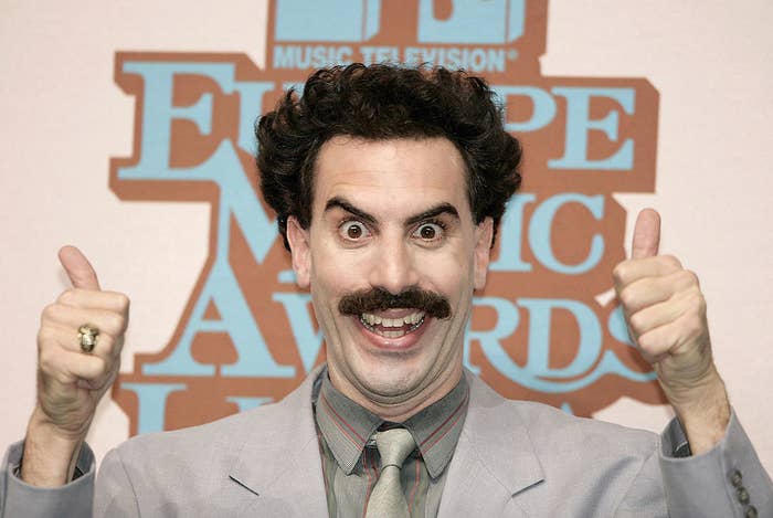Sacha Baron Cohen as Borat giving two thumbs up with a deranged smile on his face