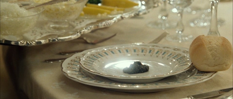 A delicate dollop of Beluga caviar on a plate, with a dinner roll on the side