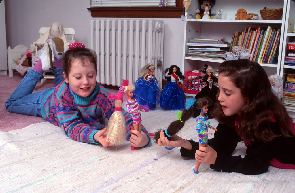 two girls playing with Barbies