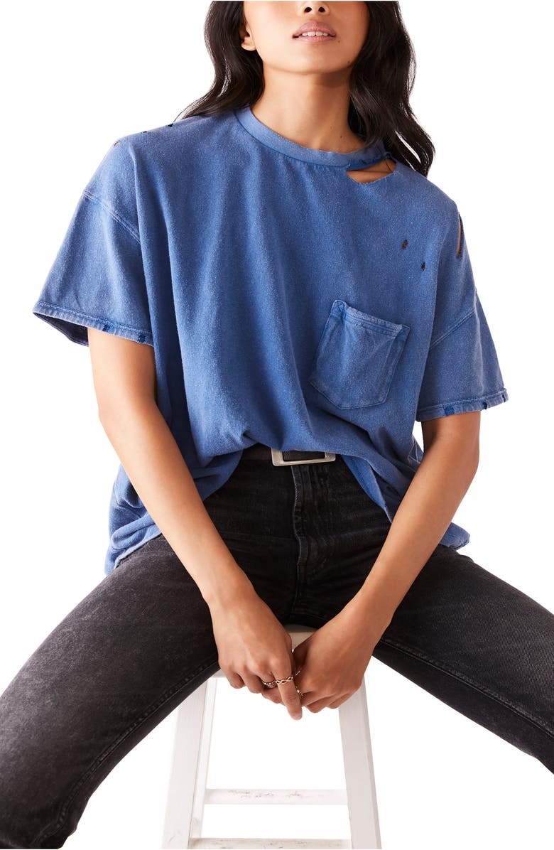 model wearing a blue ripped pocket t shirt while sitting on a stool