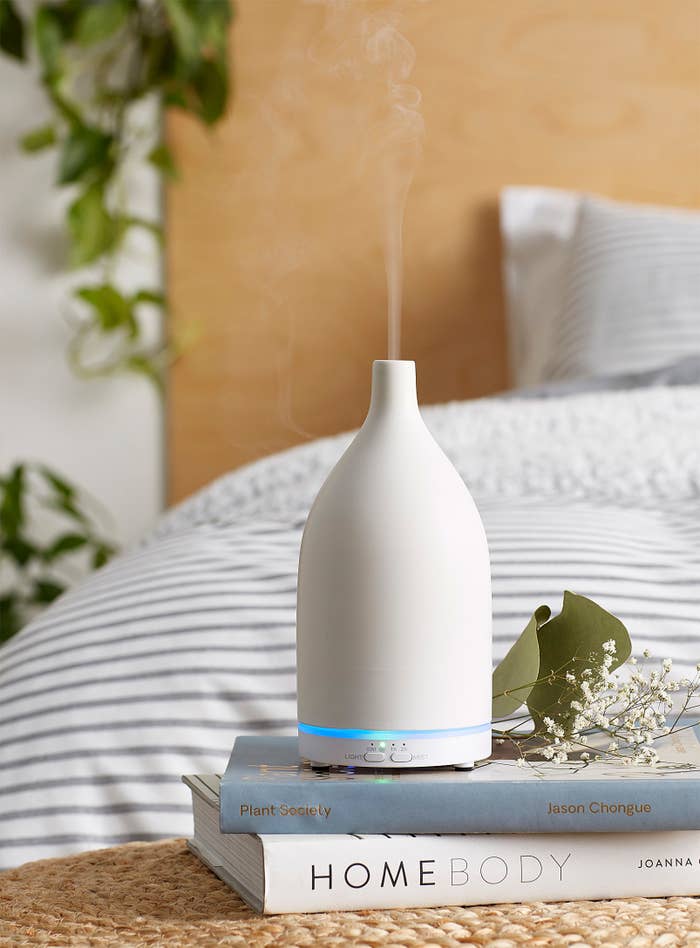 A ceramic diffuser that looks like a vase on a stack of books