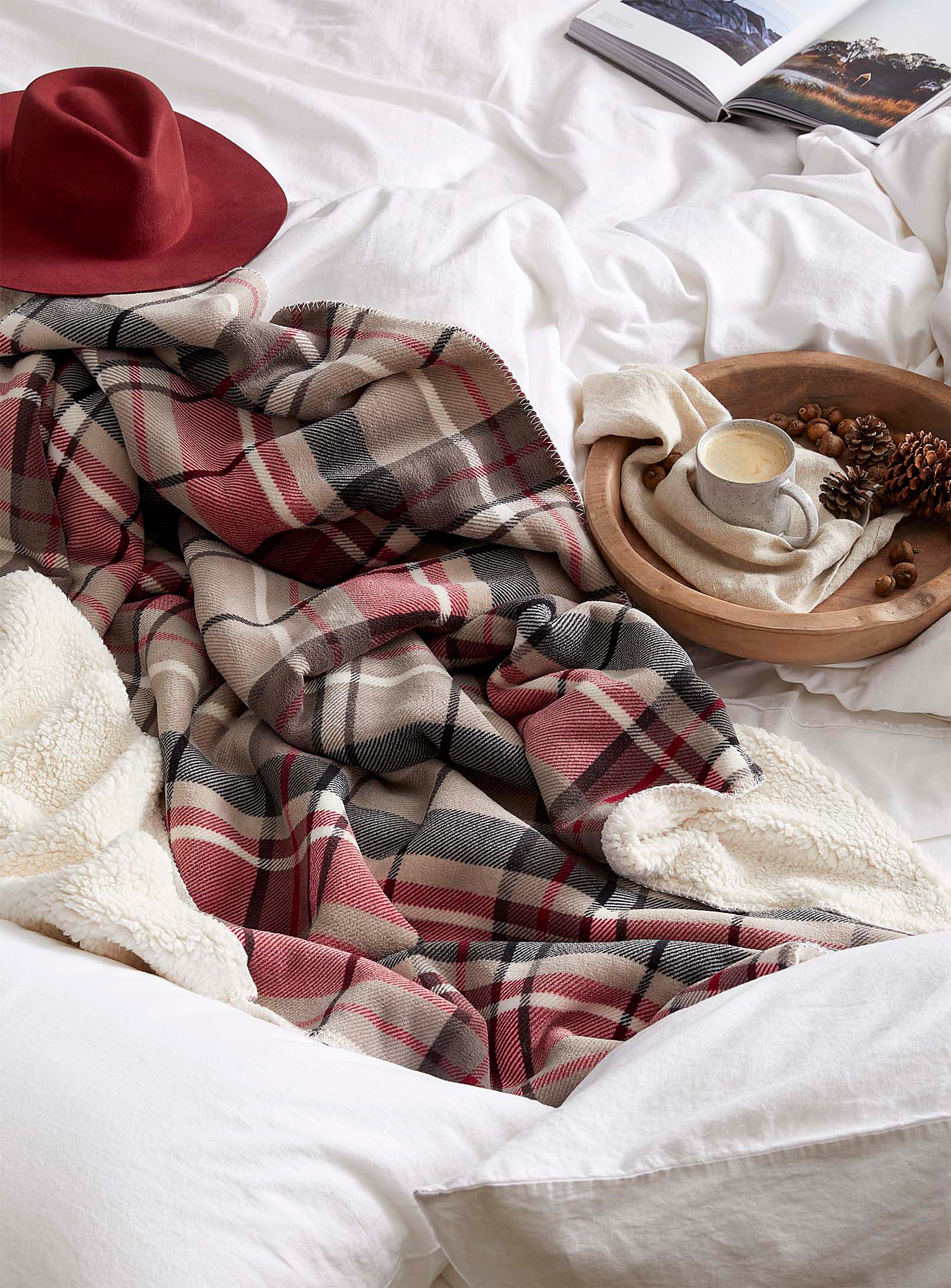 A rumpled fleece blanket on a bed next to a wooden tray with food