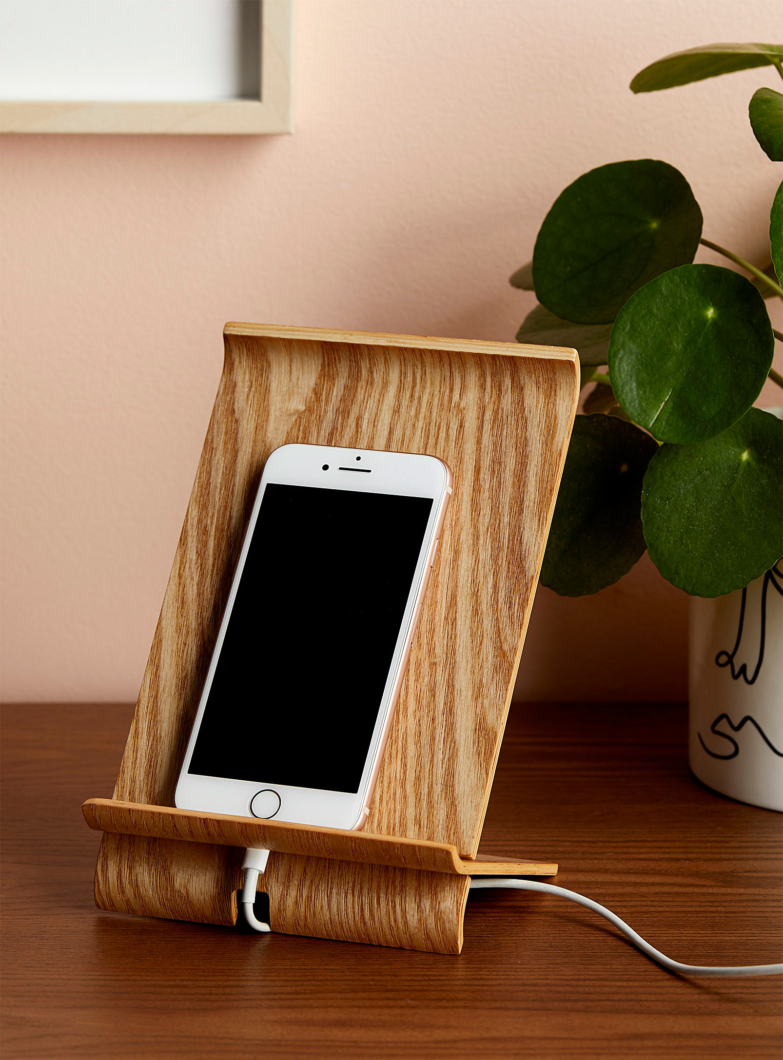 An iPhone charging and propped up on a wooden stand