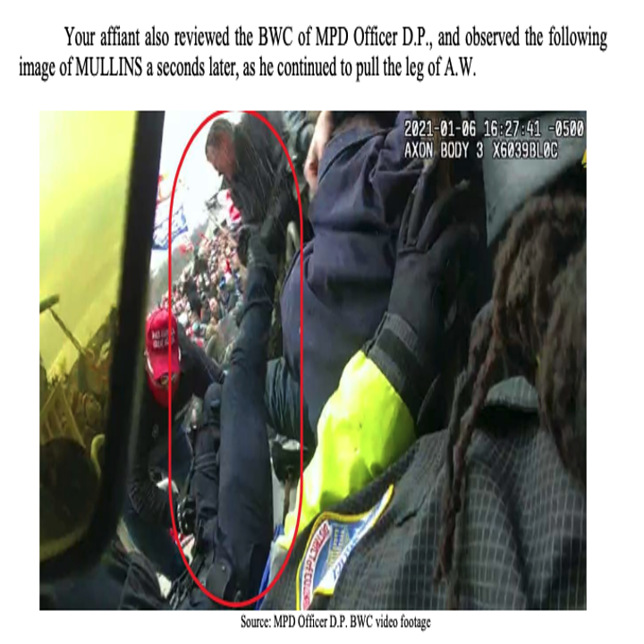 A man wearing a MAGA hat pulls on a leg of an officer lying on the ground