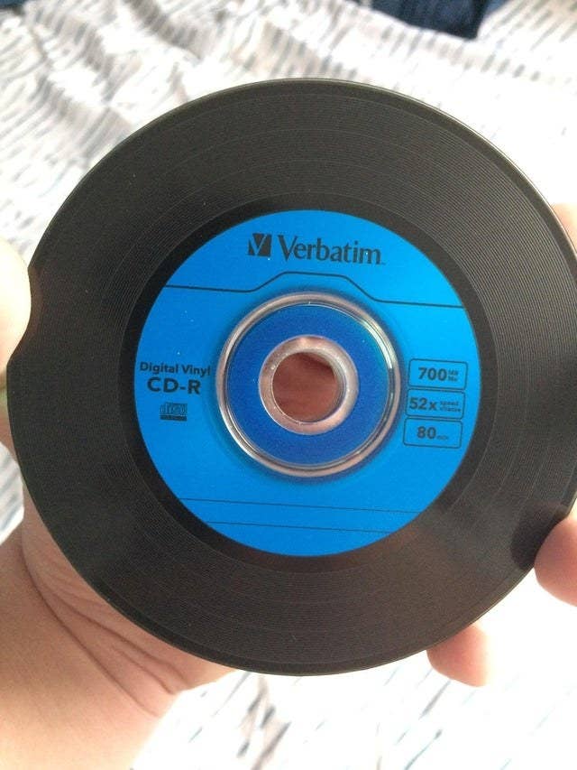 Hand holding a blank CD that looks like vinyl with a blue label 