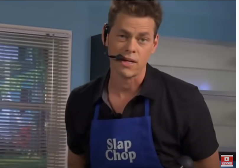 Vince talking towards the camera wearing a headpiece and a blue Slap Chop apron 