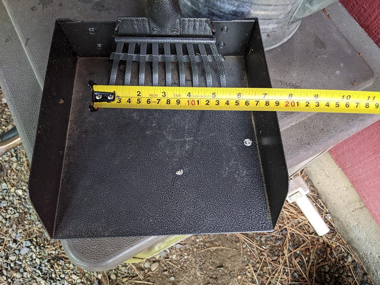 A reviewer demonstrating the size of the rake and tray with a tape-measure