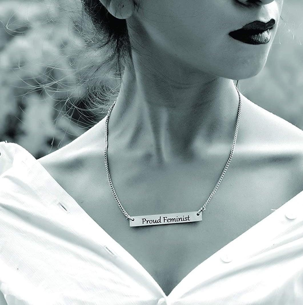 A black and white photo of a woman wearing the necklace. The rectangular locket has &quot;Proud Feminist&quot; written on it.