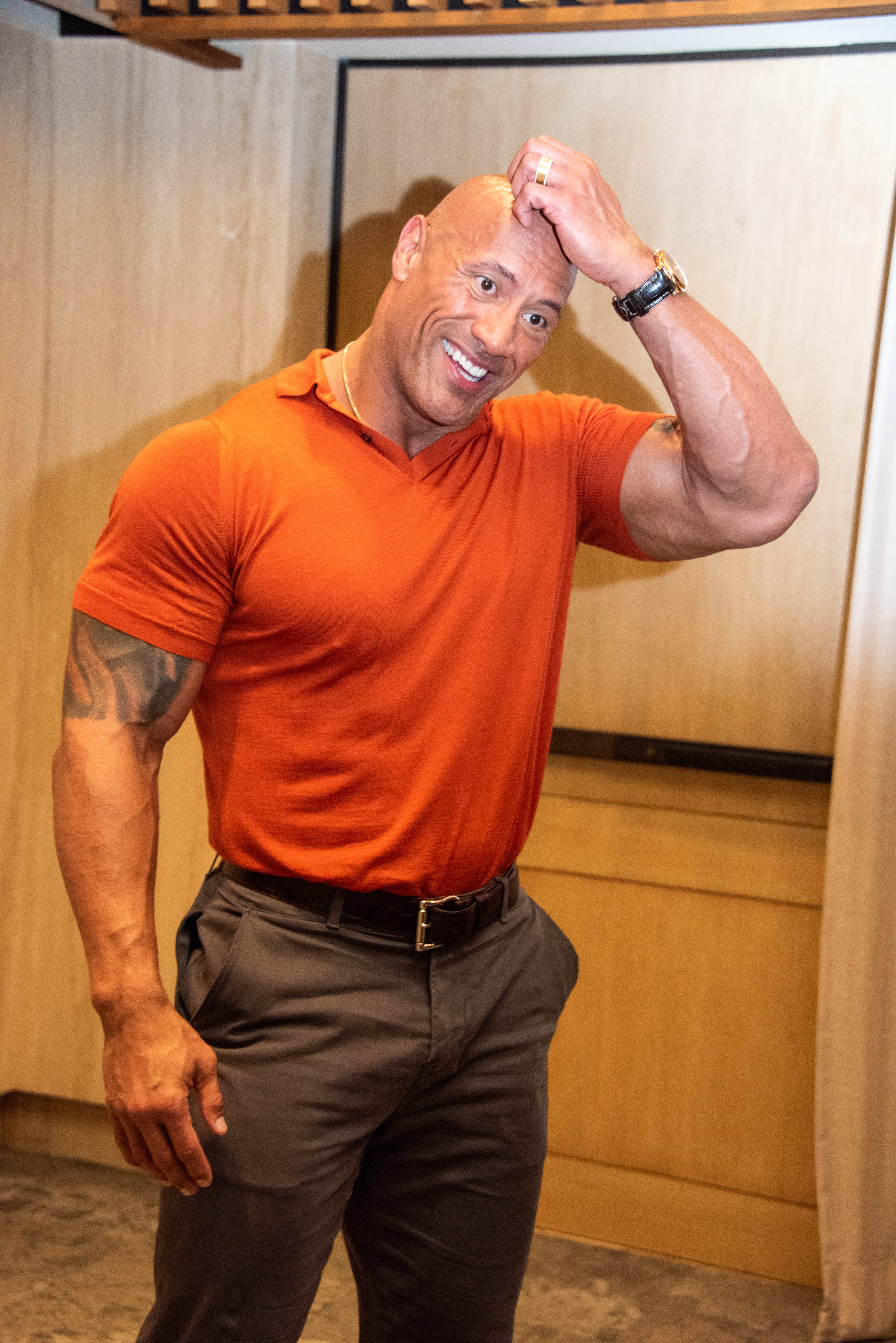 The Rock wearing a T-shirt and smiling and scratching his head 