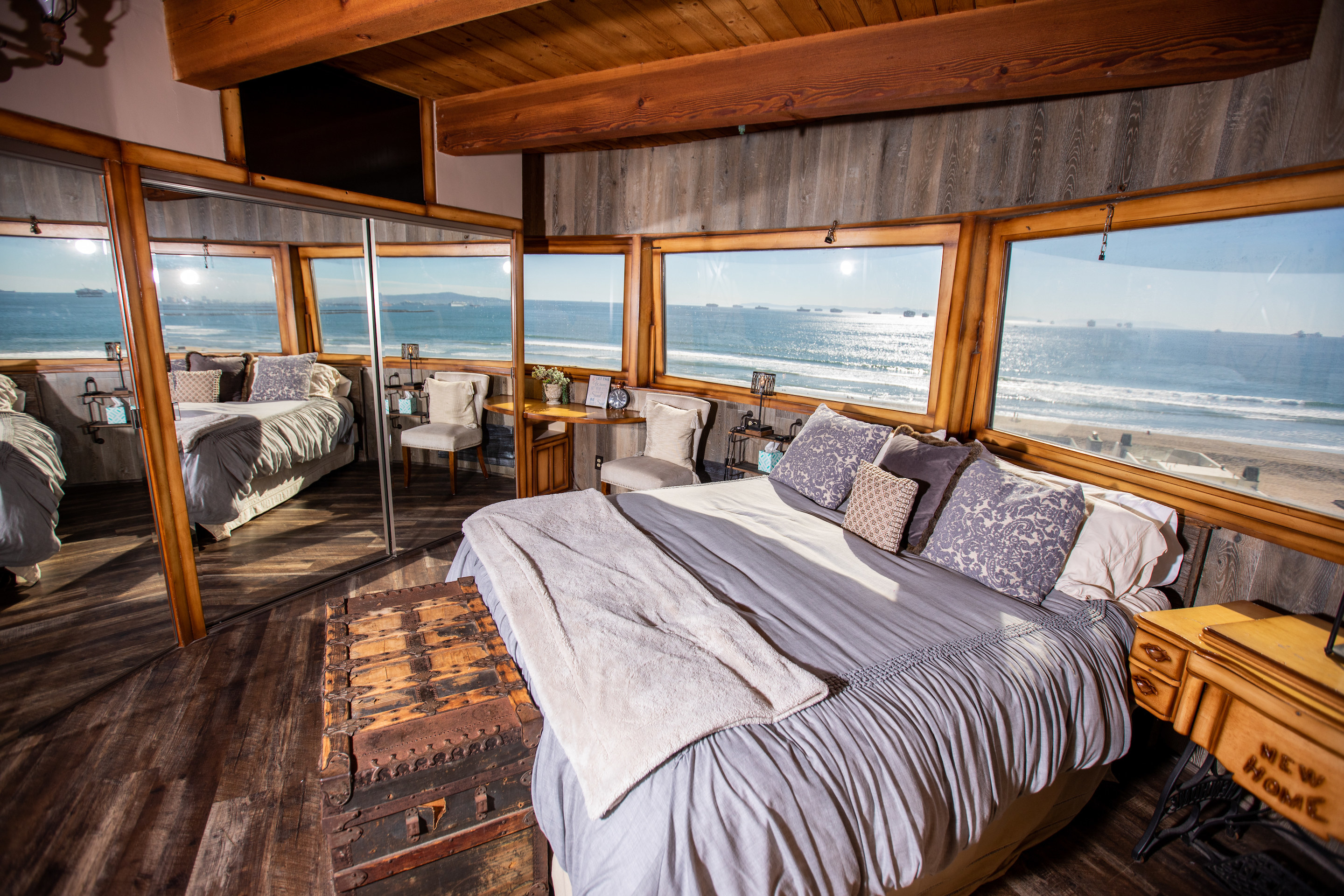 A bedroom featuring a large bed with a grey comforter and a wooden chest situated nearby