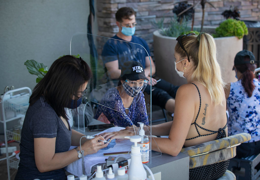 Nail technicians giving clients manicures at outdoor tables