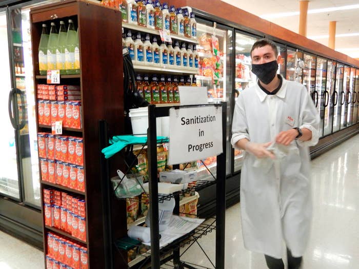 Grocery store worker sanitizing an aisle of his store