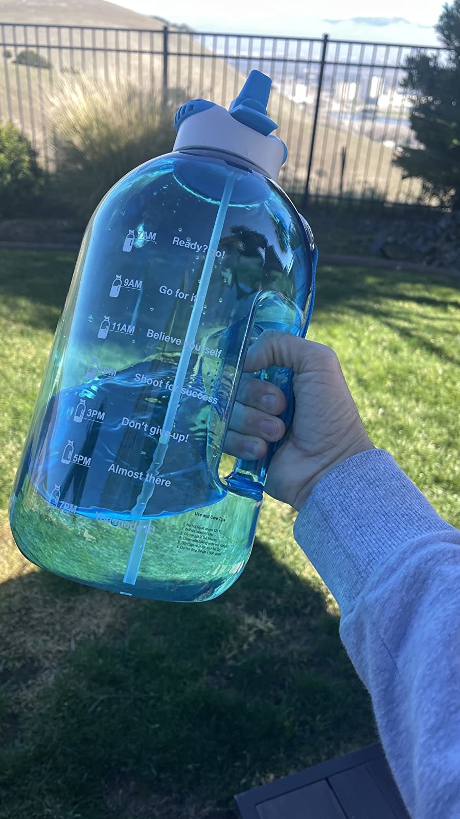 A hand holding the blue water bottle