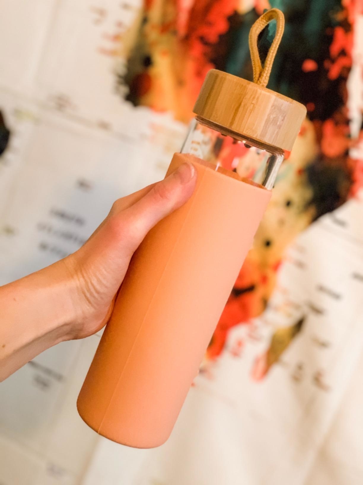 A hand holding a pink water bottle