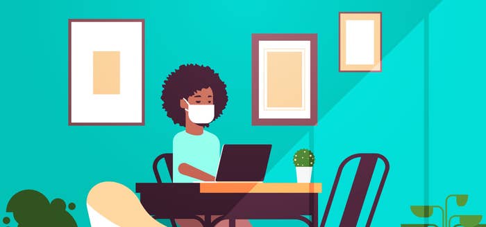 A woman working from home during the pandemic on her laptop while wearing a mask
