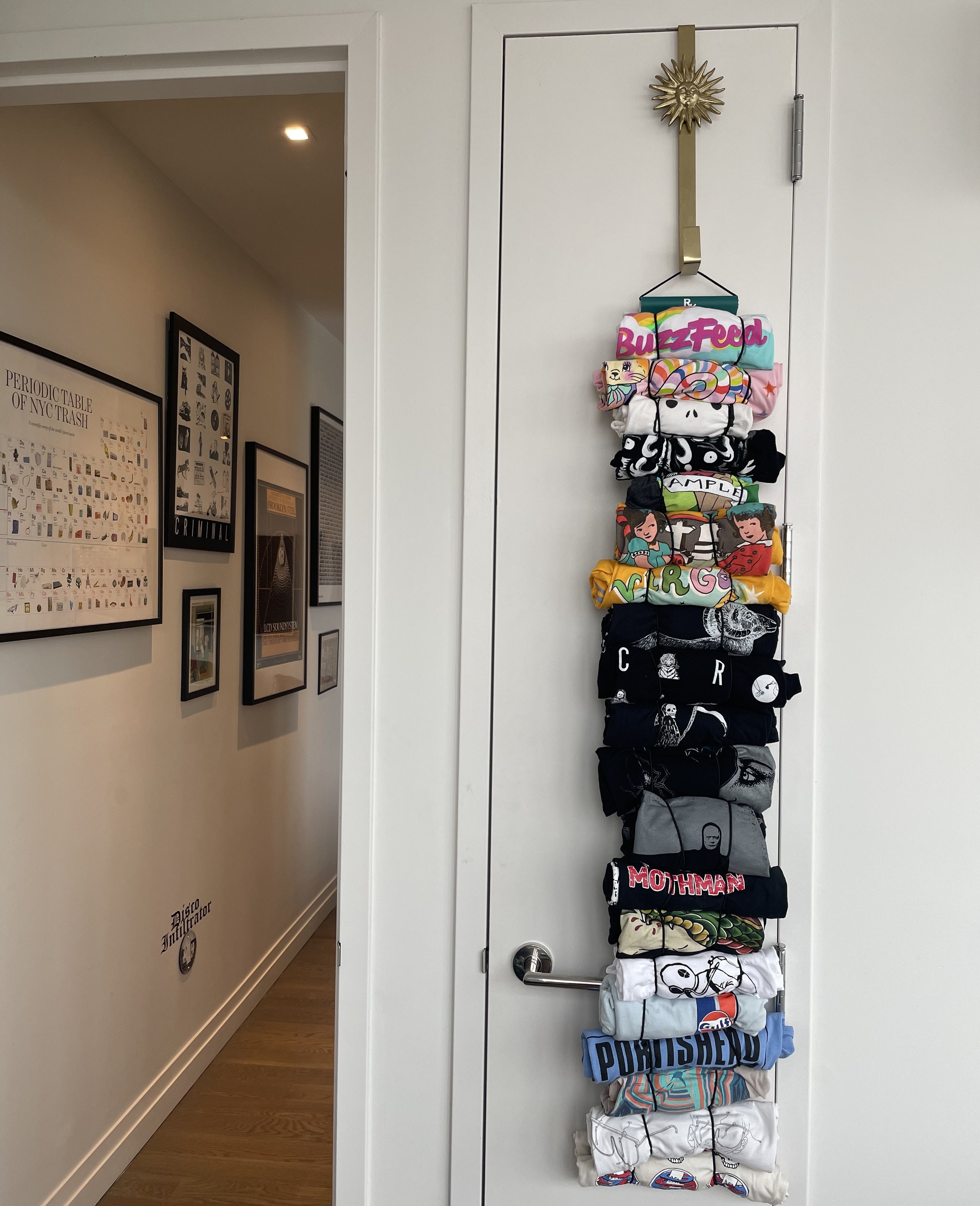 a reviewer photo of a closed closet with several shirts hanging from a hook at the top of the door. The shirts are attached by rolling them up and putting them through stretchy loops. 
