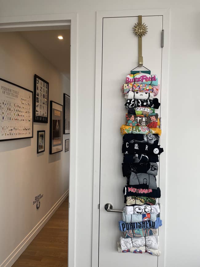 closet door closed with several shirts hanging from a hook at the top of the door. The shirts are attached by rolling them up and putting them through stretchy loops. 