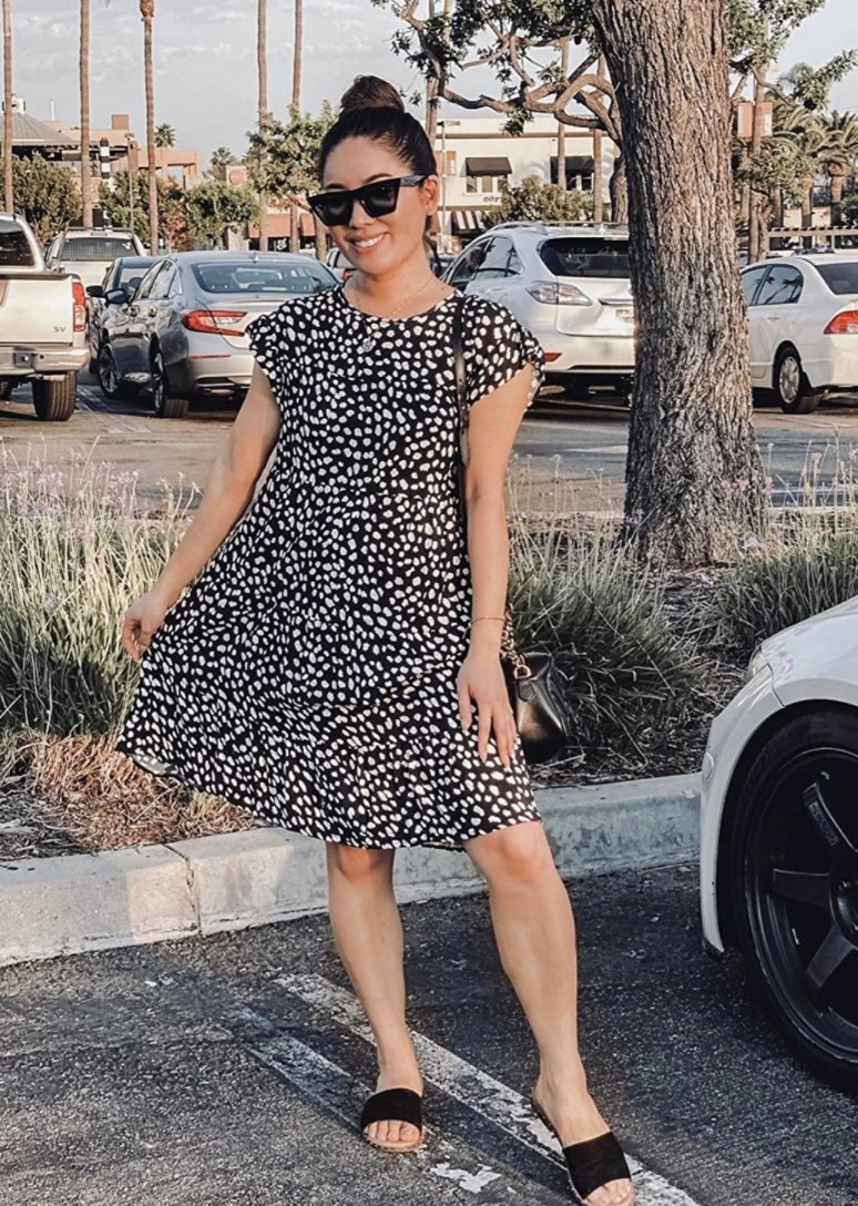 A person wearing a black dress with small white polka dots throughout