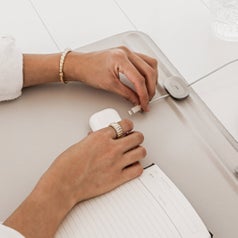 closeup of the magnetic cord holder with hands pulling in the cord to a set of AirPods