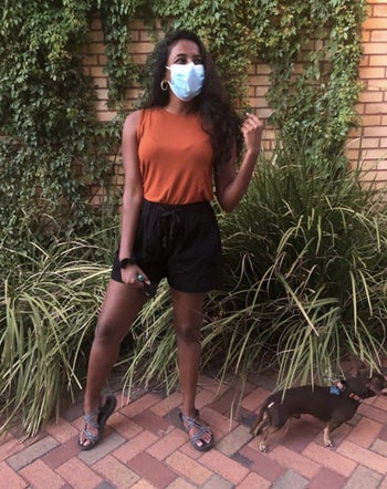 A person wearing a burnt orange top and black shorts