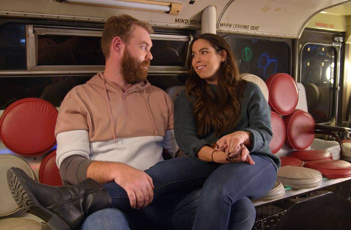 A woman sits next to a man with her legs over his lap