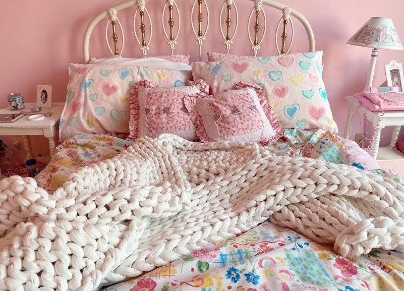 A white knit weighted blanket on a pink bed 