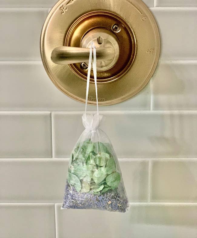 A small satchel of lavender and eucalyptus hanging from a bath handle 