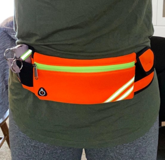 person wearing a bright orange belt bag on their waist