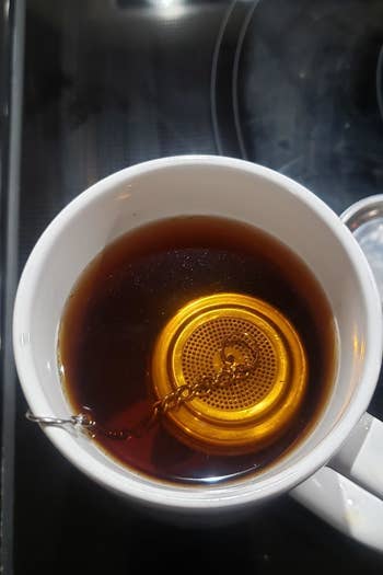 A reviewer photo of the strainer in a mug filled with black tea 