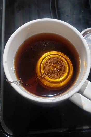 A reviewer photo of the strainer in a mug filled with black tea 