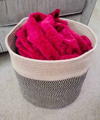 reviewer photo of a pink blanket in a black and white rope basket