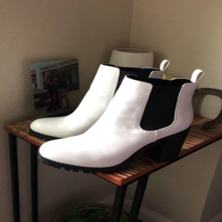 a pair of white patent leather heeled chelsea boots on a table