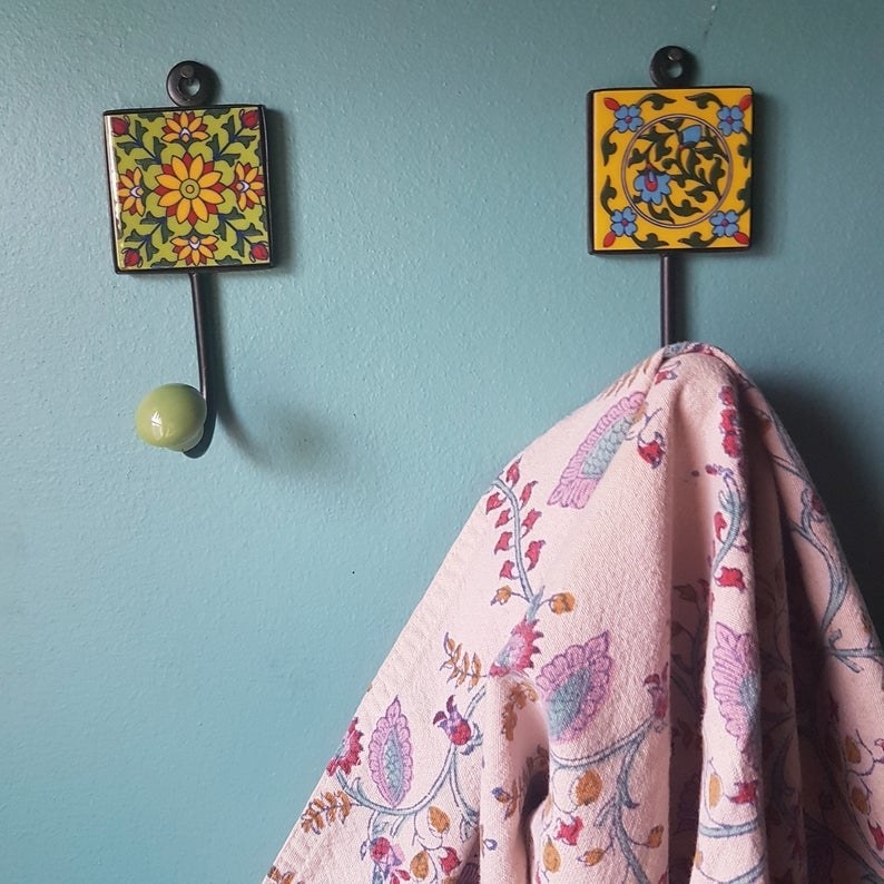 Two of the three ceramic wall hangers with a patterned blanket hanging off of one 