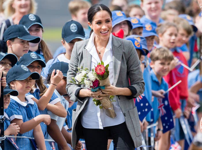 Meghan greeting school children at Dubbo Airport; she is holding bouquets of flowers