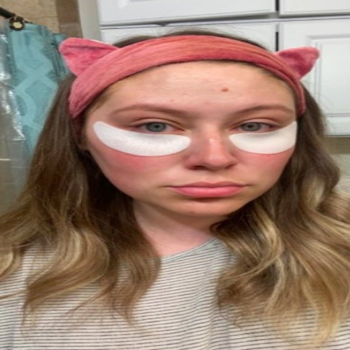 person using under-eye patches while wearing a soft headband